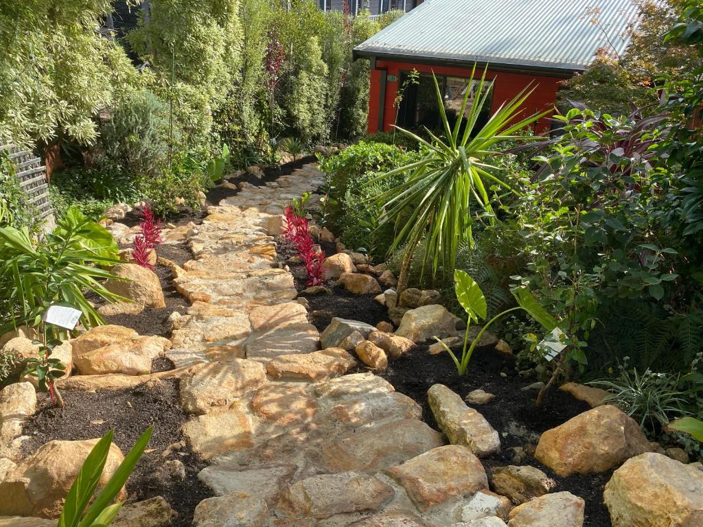 a garden with rocks and plants and a building at The Red Cottage in Wentworth Falls