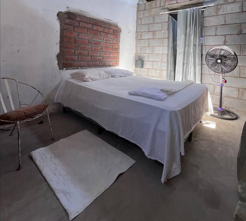 a bedroom with a bed and a brick wall at Hostal Brisas del Ometepe in Rivas