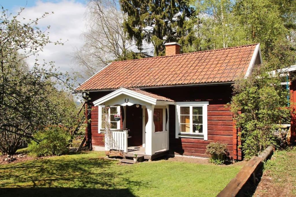 ein kleines Haus mit einer weißen Tür und einer Veranda in der Unterkunft Mysig stuga in Orsa
