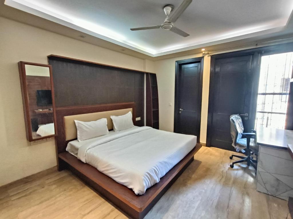 a bedroom with a bed and a desk and a chair at Greenleaf Apartment and Suites, Greater Kailash 1 in New Delhi