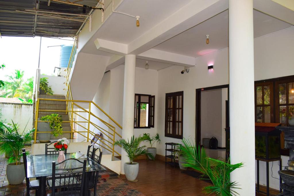 uma sala de jantar com mesa, cadeiras e plantas em White Villa Hotel em Trincomalee