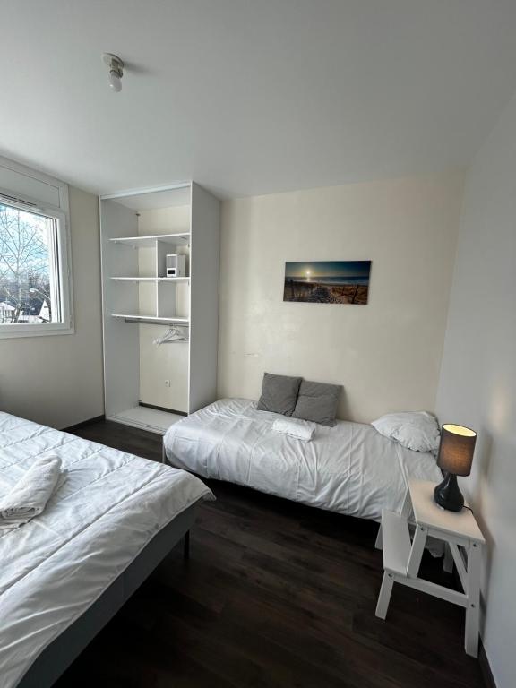 ein Schlafzimmer mit 2 Betten und einem Tisch mit einer Lampe in der Unterkunft Duplex lumineux tout équipé/RER D/Balcon/Parking in Corbeil-Essonnes