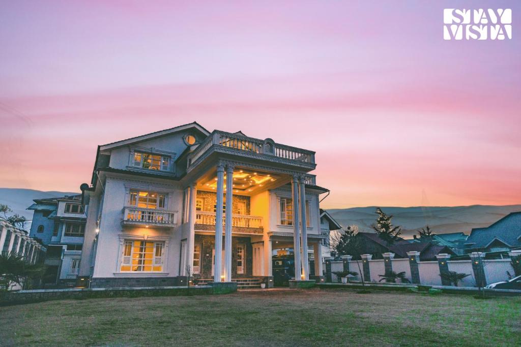 a large house with a sunset in the background at StayVista at Midsummer Moon - Mountain View with Courtyard in Srinagar
