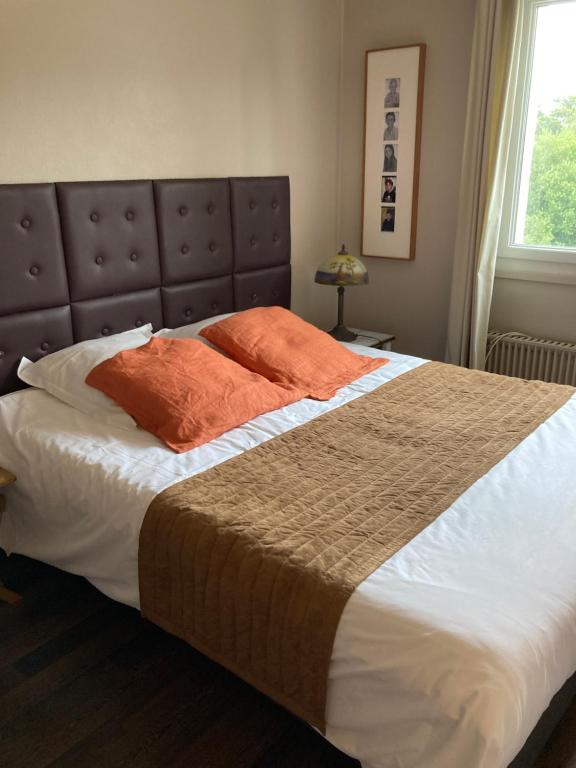 um quarto com uma cama grande e almofadas laranja em Maison Blanche em Coudeville