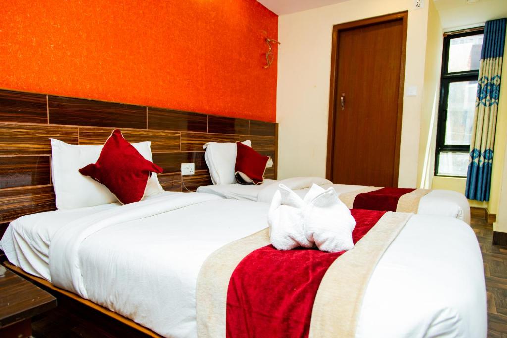a bedroom with two beds with red and white pillows at Hotel Everest Regency in Kathmandu