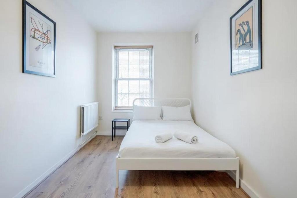 a white bed in a white room with two windows at APlaceToStay Central London Apartment, Zone 1 OX in London
