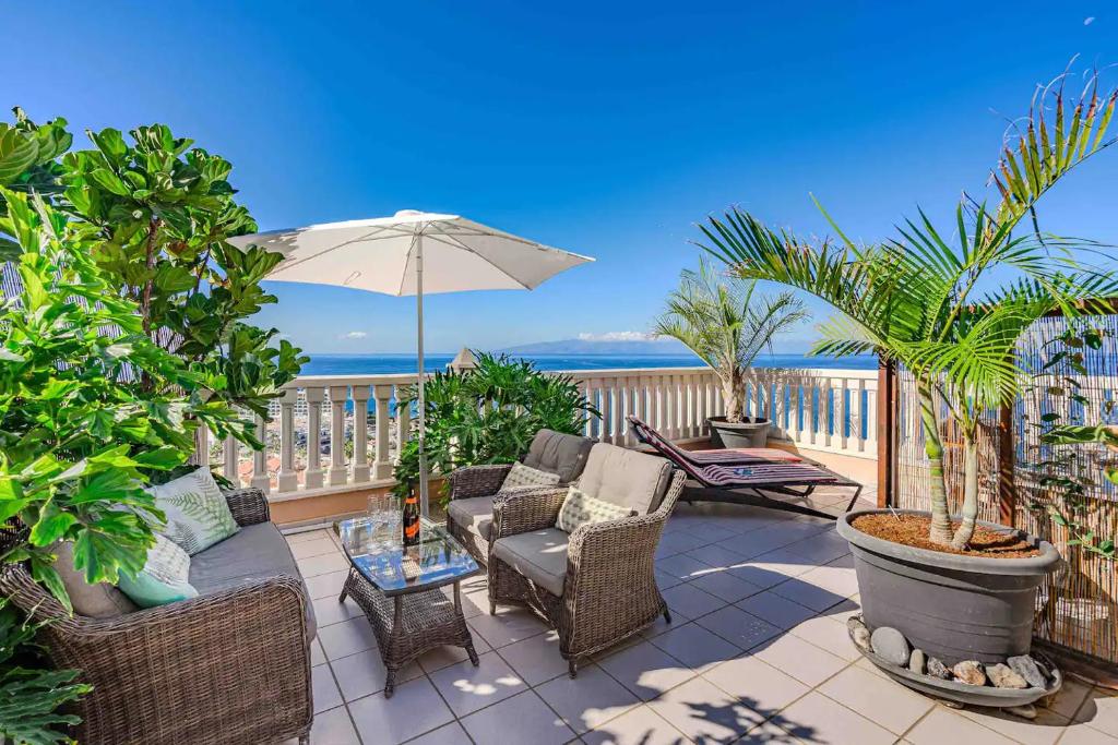 une terrasse avec des chaises et un parasol et l'océan dans l'établissement Los Gigantes Buenavista Ocean View Apartment, à Acantilado de los Gigantes