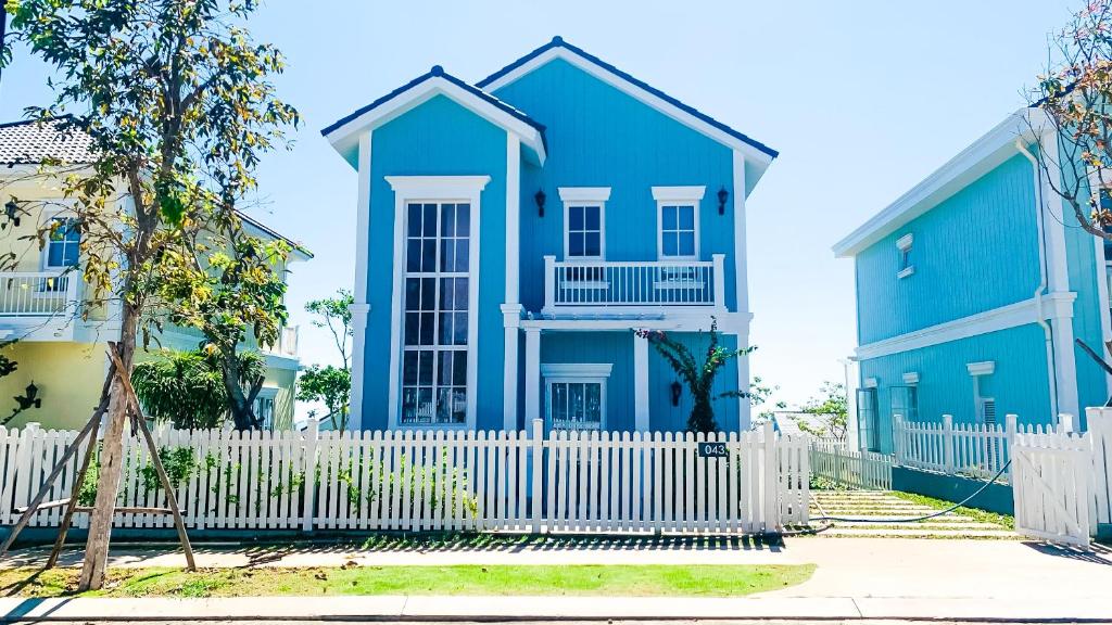 een blauw huis met een wit hek bij Kat House Novaworld Phan Thiết in Bình Tú