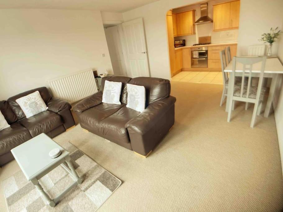 a living room with a leather couch and a table at Central Retford 2 bed quiet apartment with parking in Retford