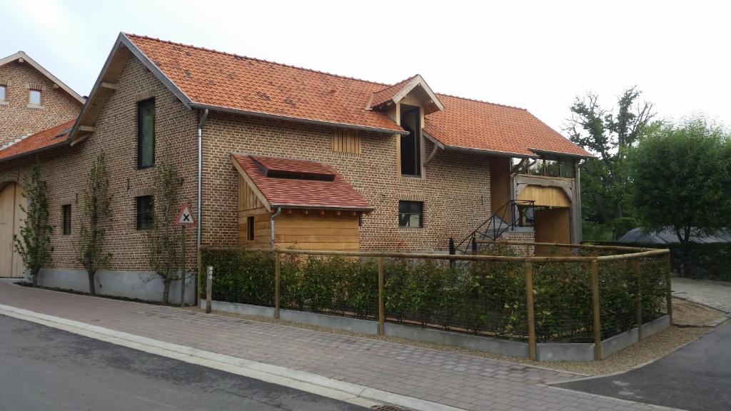 une maison en briques avec une clôture devant elle dans l'établissement Huize D'Huys, à Riemst