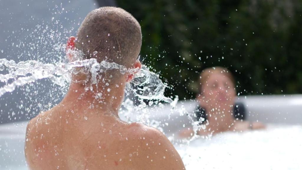 un joven jugando en una fuente en una piscina en Spa de campagne Ressource gite THALASSO privatisée INCLUS, en Dormelles