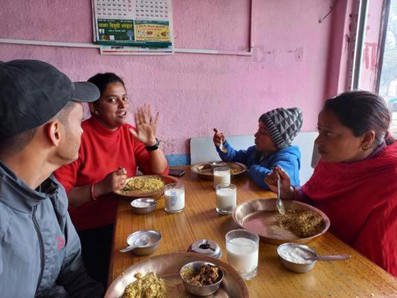 un grupo de personas sentadas alrededor de una mesa comiendo comida en Mankamana Resturant and lodge, en Butwāl