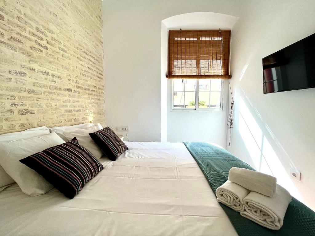a white bed in a room with a brick wall at Casa 1928 - 1 IZQ - Plaza de España in Seville