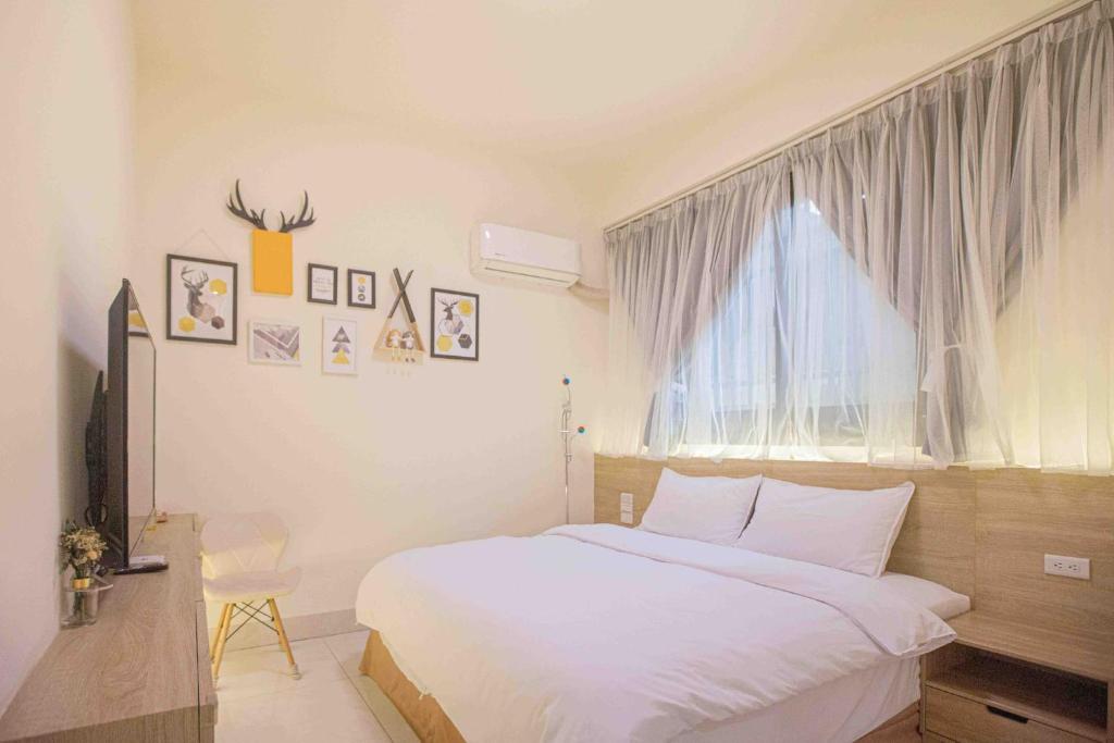 a bedroom with a large white bed and a window at 里舍民宿 in Jincheng