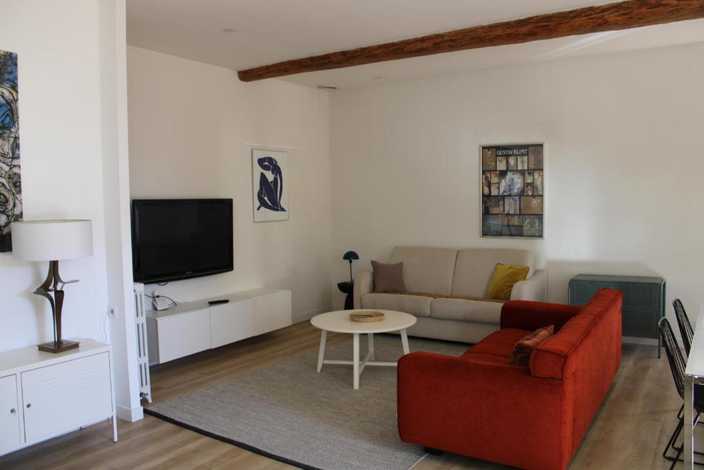 een woonkamer met een rode bank en een tv bij Maison chaleureuse avec grande terrasse in Nîmes