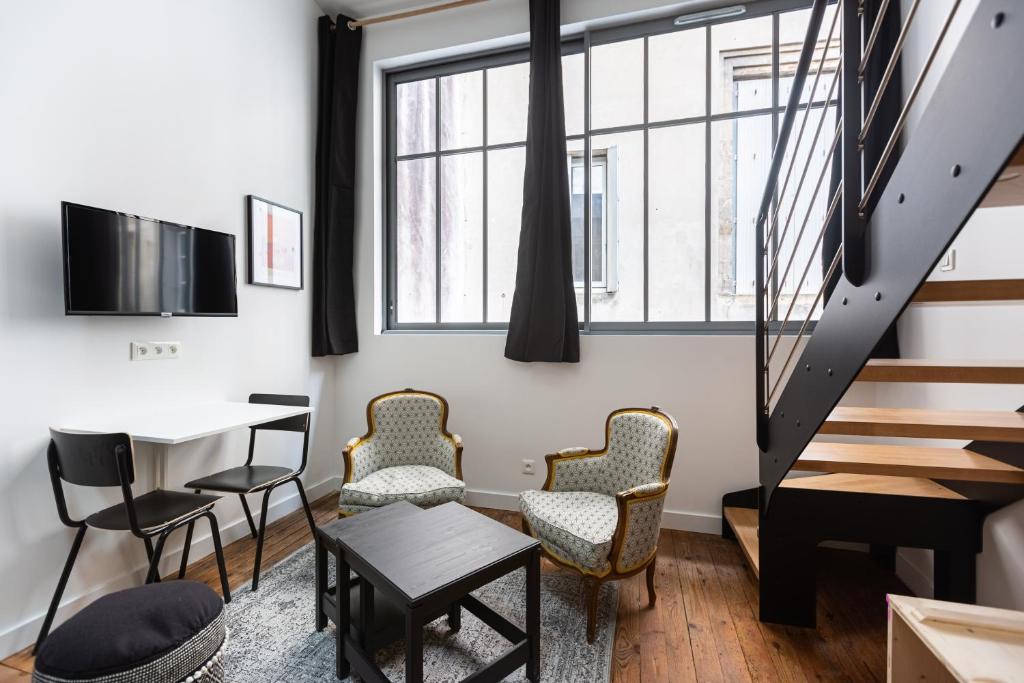 - un salon avec des chaises, une table et des escaliers dans l'établissement Le Victor Hugo - Centre-ville Bordelais, à Bordeaux