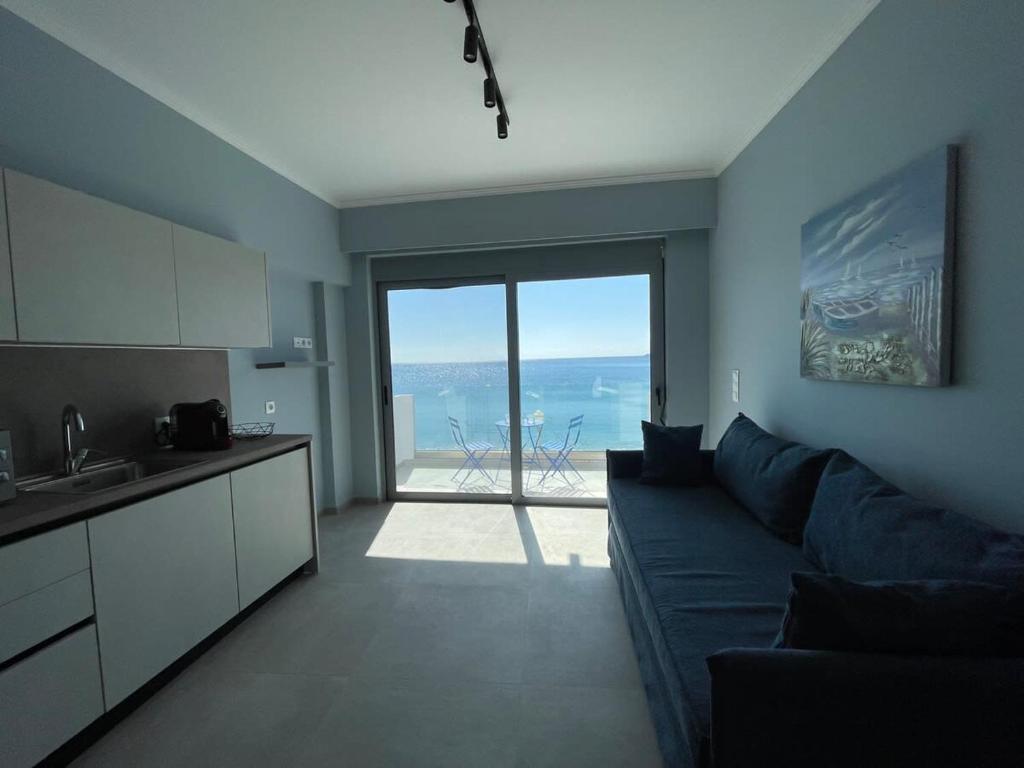 a living room with a blue couch and a view of the ocean at Charaki Sea Breeze Modern Studio with Balcony in Haraki