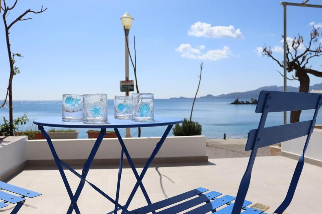 a blue table and chairs with a view of the ocean at Charaki Escape Chic Studio with Seafront Patio in Haraki