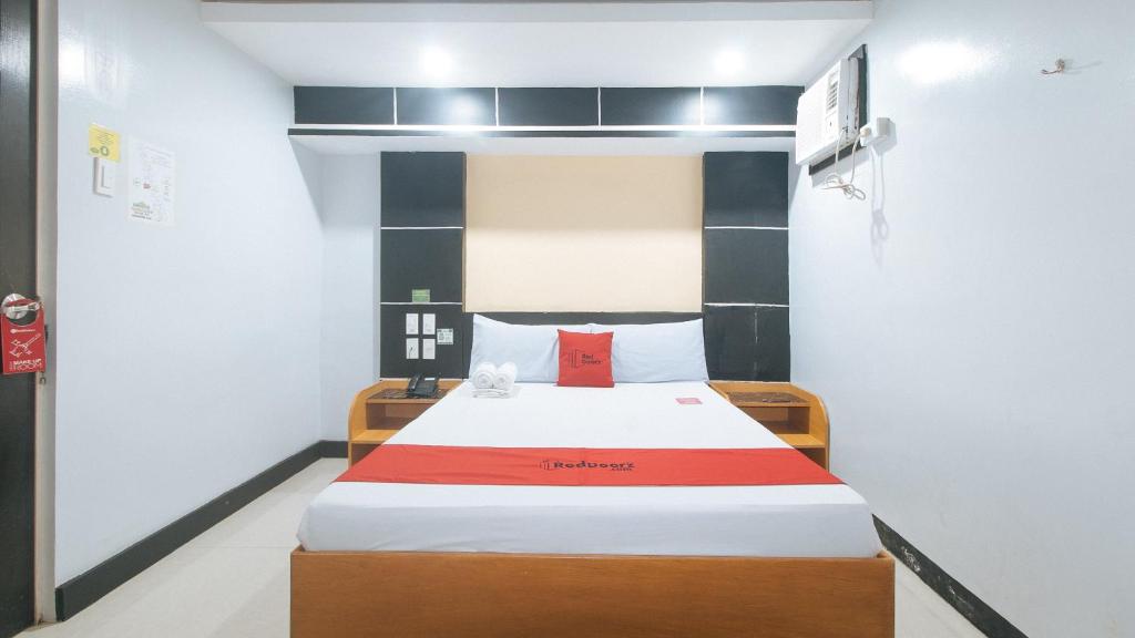 a bedroom with a large bed with a red pillow at RedDoorz at Ranchotel Alabang in Manila
