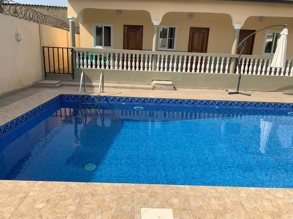 a large blue swimming pool in front of a house at pavillon « lilas » à dagué-togo in Dagé