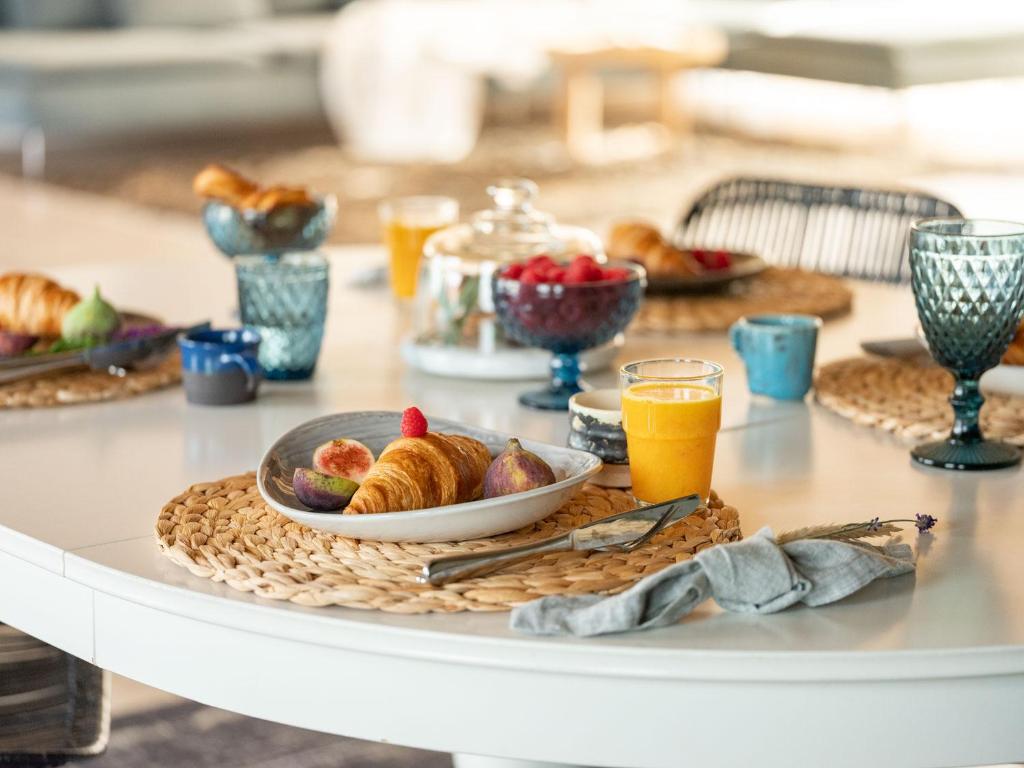 a table with a plate of croissants and orange juice at Guest House Skrablas in Rucava