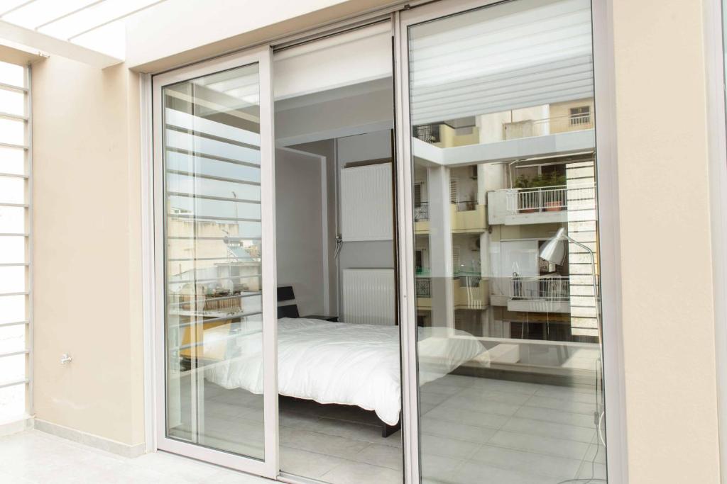 een slaapkamer met glazen schuifdeuren en een bed bij Bright Loft With Terrance - Next to Metro Kerameikos in Athene