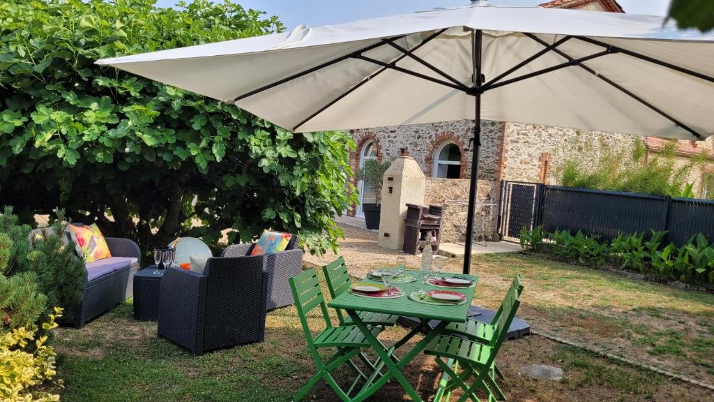 a table and chairs under an umbrella in a yard at Le grand clos, 3 étoiles in Pont-Saint-Martin