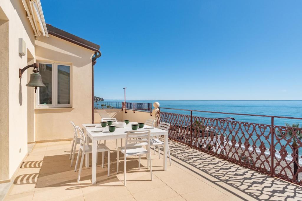 a white table and chairs on a balcony with the ocean at RivieraRent La Terrazza sul mare in Pietra Ligure