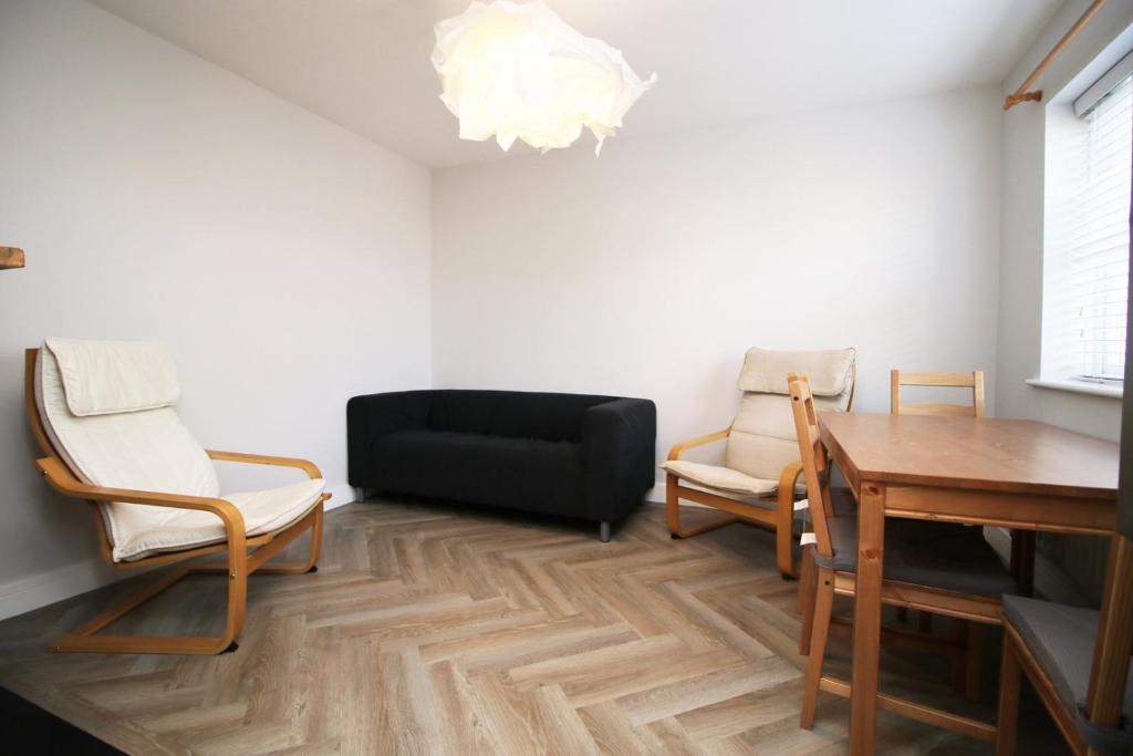 ein Wohnzimmer mit Stühlen, einem Tisch und einer schwarzen Couch in der Unterkunft Cohost Partners, Monthly/Weekly discounts in Bristol