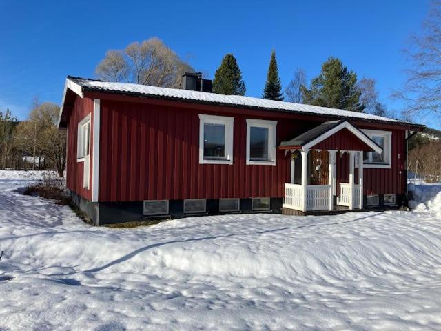 een rood huis met sneeuw op de grond voor de deur bij Villa Marlise in Hammarstrand