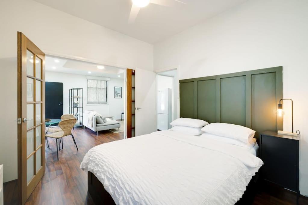 a bedroom with a large bed with a green headboard at Cute & Cosy - Walk to City, Harbour and Museum in Sydney