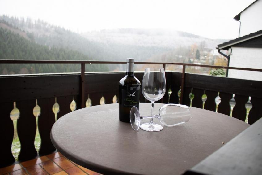 una mesa con una botella de vino y dos copas en Tal Blick 3-Zimmer Nordenau/ Winterberg, en Schmallenberg