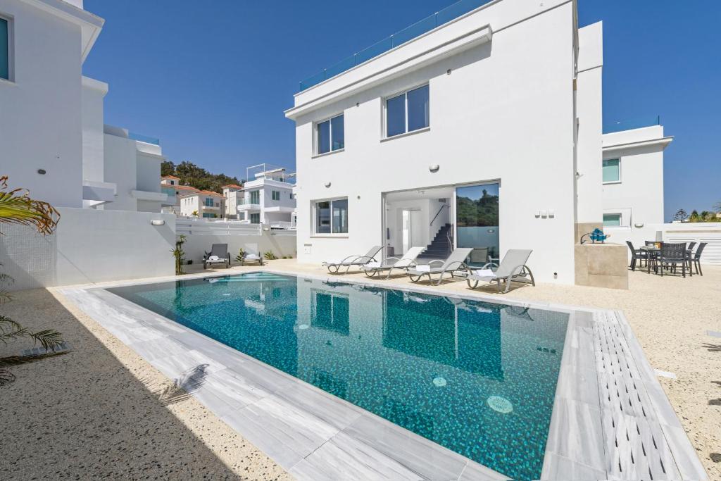 a swimming pool in front of a white house at Green Bay Villa #15 in Protaras