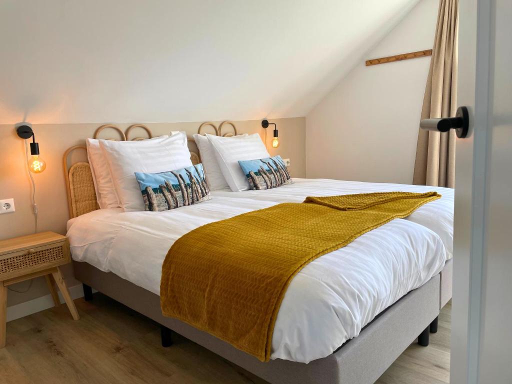 a bedroom with a large bed with white sheets and pillows at Bij het bos Texel in De Koog