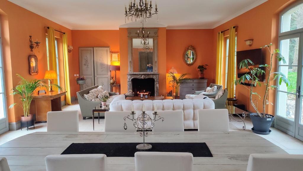 una sala de estar con muebles blancos y paredes de color naranja. en La Demeure du Figuier, en Évran