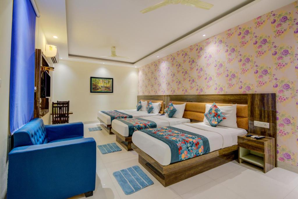 a bedroom with two beds and a blue chair at Hotel Smart Plaza Delhi Airport in New Delhi