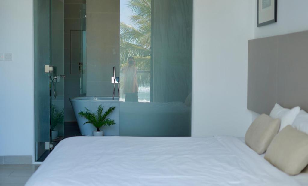 1 dormitorio con cama blanca y bañera en Dreamers House Vung Tau - a beachfront villa, en Vung Tau
