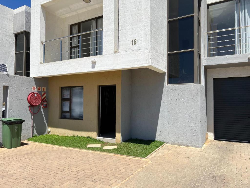 a white house with a red fire hydrant in front of it at Apartment close to Golf Course! in Windhoek