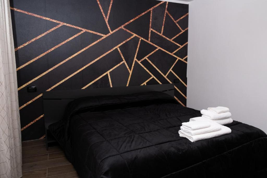 ナポリにあるNapoli Center Suite Palmentieriのベッドルーム1室(黒いベッド1台、白いタオル付)
