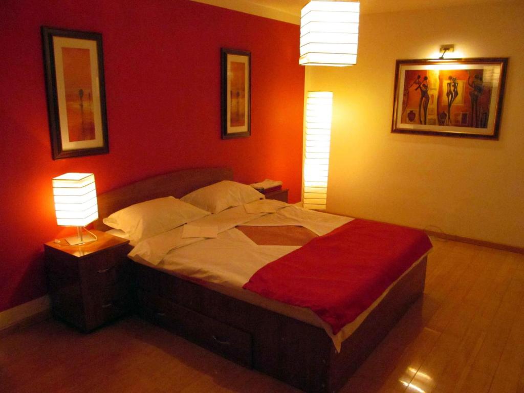 シビウにあるApartament Liraのベッドルーム1室(赤い壁のベッド1台、ランプ2つ付)