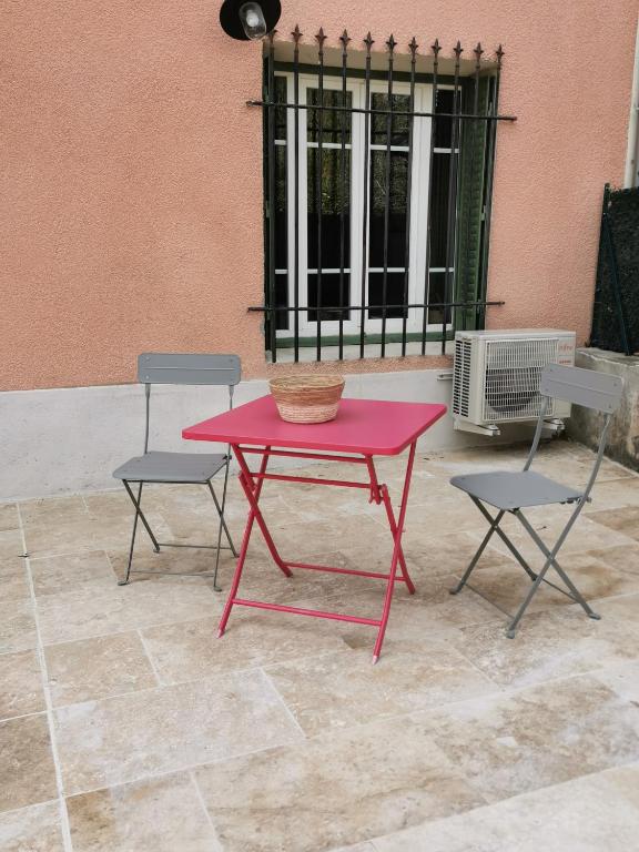 une table et des chaises rouges devant un bâtiment dans l'établissement Charbon studio climatisé parking terrasse, à Villeneuve-lès-Avignon