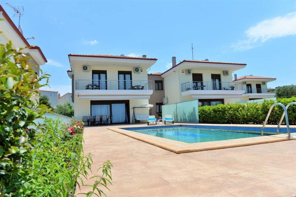 a villa with a swimming pool in front of a house at Villas Hanioti in Hanioti