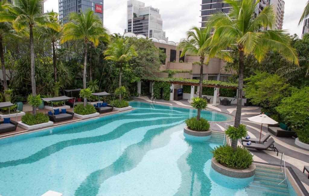 An elevated view across a winding pool with loungers, palms and landscaped islands.