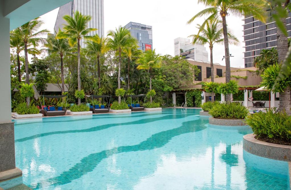 A broad turquoise pool framed by palms and landscaped planting in a city setting.