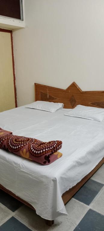 uma grande cama branca com uma cabeceira de madeira em Shree Shivaya Guest House em Ujaim