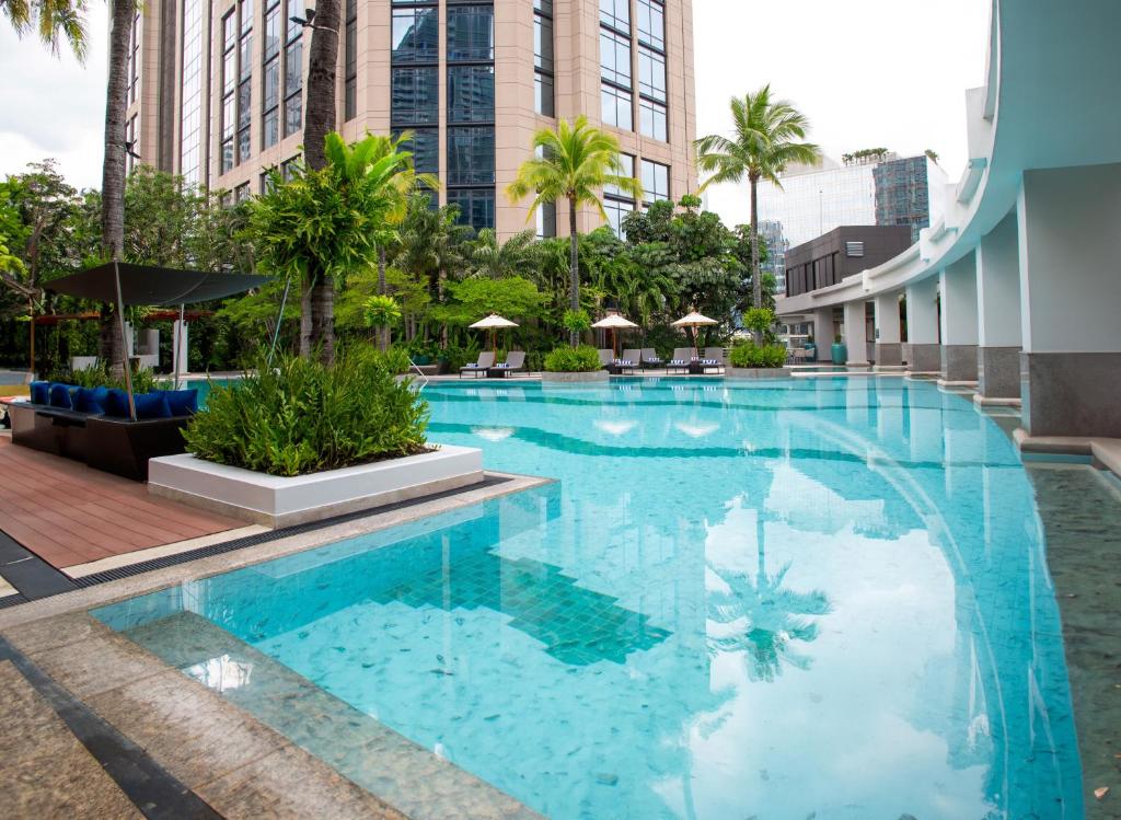 An urban pool deck with a long blue pool, palms and surrounding hotel architecture.