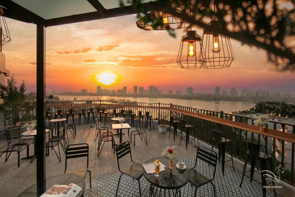 a restaurant with tables and chairs on a balcony with a sunset at Westlake Pearl Apartment & Hotel - By Pegasy Group in Hanoi
