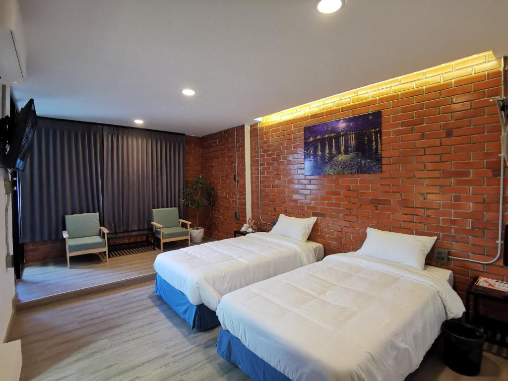 1 dormitorio con 2 camas y pared de ladrillo en BETONG HELLO GUESTHOUSE, en Betong