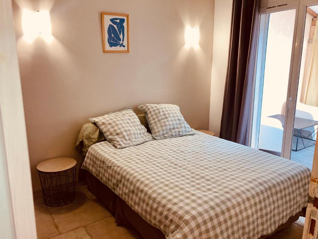 a small bedroom with a bed with a checkered blanket at Appartement avec grande terrasse in Martigues