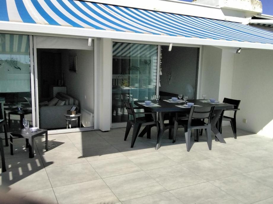 une table et des chaises noires sur une terrasse avec un toit dans l'établissement Flat With Terrace And Harbour View, au Grau-du-Roi